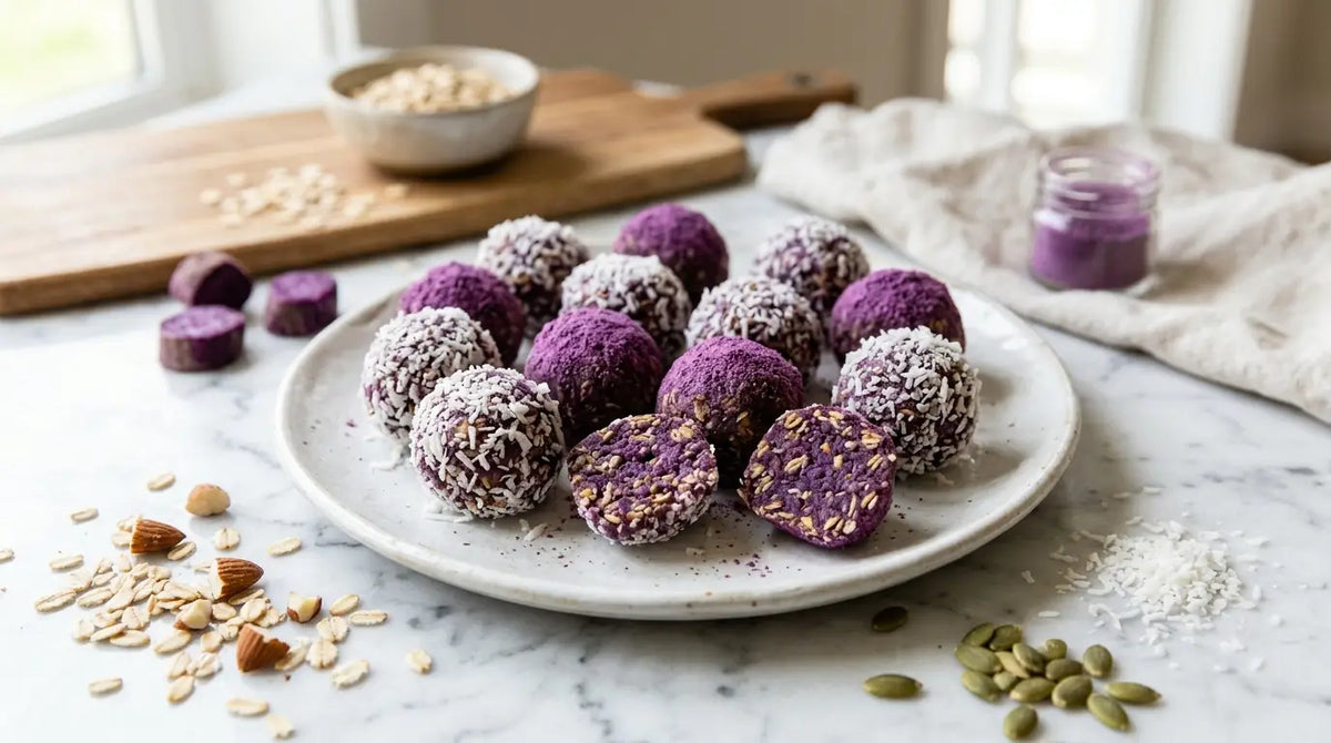 Assiette d'energy balls violettes à l'ube, certaines enrobées de noix de coco râpée, une coupée en deux